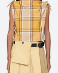 Woman wearing a yellow plaid top and beige pants on a white background