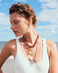 Woman wearing colorful necklaces on a beach with blue sky and ocean in the background