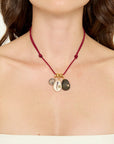 Necklace with three charms on a red cord worn by a person