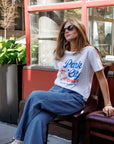 Woman wearing a 'Park City' t-shirt sitting on a chair outdoors.