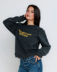 Woman wearing a dark gray sweatshirt with yellow text against a white background