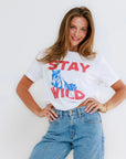 Woman wearing a white t-shirt with 'Stay Wild' text and blue jeans against a white background