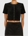 Model wearing studded black shirt and skirt on white back ground