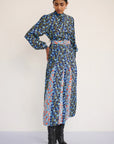 Woman wearing a long floral dress with a belt on a white background