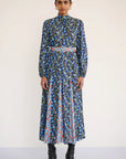 Woman wearing a long floral dress with a belt on a white background, front