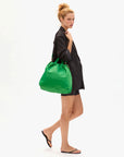 Woman holding a green bag against a white background