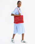 Person holding a red woven bag against a white background
