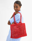 Woman holding a red woven handbag against a white background