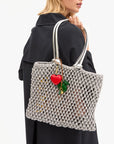 Person holding a textured handbag with a heart charm on a white background