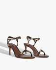 Pair of high-heeled sandals with gold accents on a white background