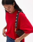 Person wearing a red sweater with a black and gold handbag on a white background