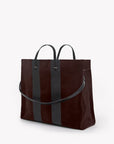 A dark brown suede tote bag with two vertical black leather stripes and black leather handles, shown on a clean white background.
