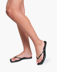 Person wearing emerald flip-flops on a white background