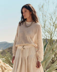 Woman wearing a beige knit top and skirt in a desert setting