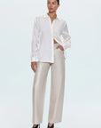 Woman wearing a white blouse and beige pants on a white background