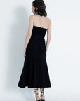 Woman wearing a black strapless dress with a white background back view