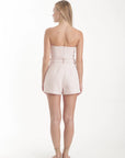 Woman wearing a strapless pink set on a white background, back view