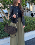 Woman in black jacket and green pants with leopard print bag outdoors