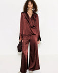 Woman wearing a burgundy satin suit with a white background