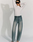 model wearing a rhinestone blue jean with a long sleeve white top and black sunglasses on a white background
