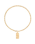 A gold chain necklace featuring a small rectangular domino pendant with raised dots, displayed against a solid white background.
