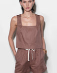 Woman wearing a brown sleeveless top and shorts set on a white background
