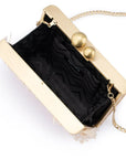 A gold-tone clutch bag with a black patterned lining, featuring two spherical gold clasp buttons and a gold chain strap, shown on a white background.