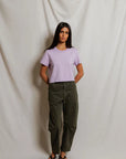 model wearing a purple tee and green pants on a white background