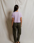 model wearing a purple tee and green pants on a white background, back view
