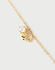 Gold necklace with a bow-shaped pendant on a light gray background detail view