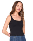 Woman wearing a black tank top and blue jeans on a white background