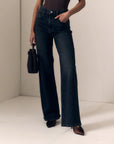 model wearing a strapless brown top with dark jeans on a cream background