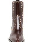 A dark brown leather ankle boot with pointed toe, studded details, and a pull tab, shown against a plain white background.