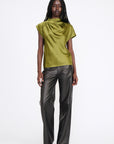Woman wearing a green top and gray pants on a white background
