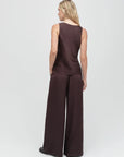 Woman wearing a brown sleeveless top and wide-leg pants on a white background