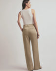 Woman wearing a white sleeveless top and beige high-waisted pants on a plain background, back view
