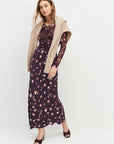 Woman wearing a floral dress with a beige cardigan on a white background front view