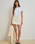 Woman wearing a white t-shirt and beige skirt against a plain background, front
