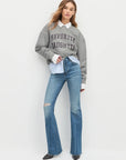Woman wearing a gray sweater with 'Favorite Daughter' text and blue jeans on a white background front view