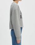 Person wearing a gray sweatshirt with text on a light gray background front view