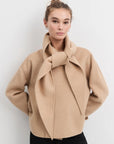 Woman wearing a beige coat against a white background