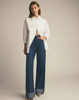 Woman wearing a white blouse and blue jeans on a plain background