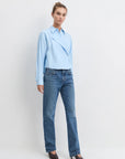 Model wearing the light blue stripe jenni top with jean and heels on a white background