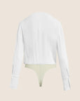 A white long-sleeve cropped shirt shown from the back, layered over a pale yellow-green thong, against a solid light beige background.