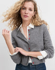 Woman wearing a gray cardigan with red buttons on a white background