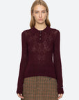 Woman wearing a burgundy patterned shirt and plaid skirt on a white background
