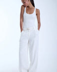 Woman wearing a white sleeveless top and wide-leg pants on a white background