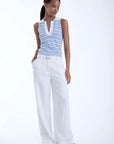 model wearing Kira sky sleeveless stripe top with white pants on a white background