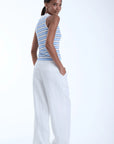 model wearing Kira sky sleeveless stripe top with white pants on a white background, back