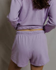 model wearing a purple lounge set on a white background, back view